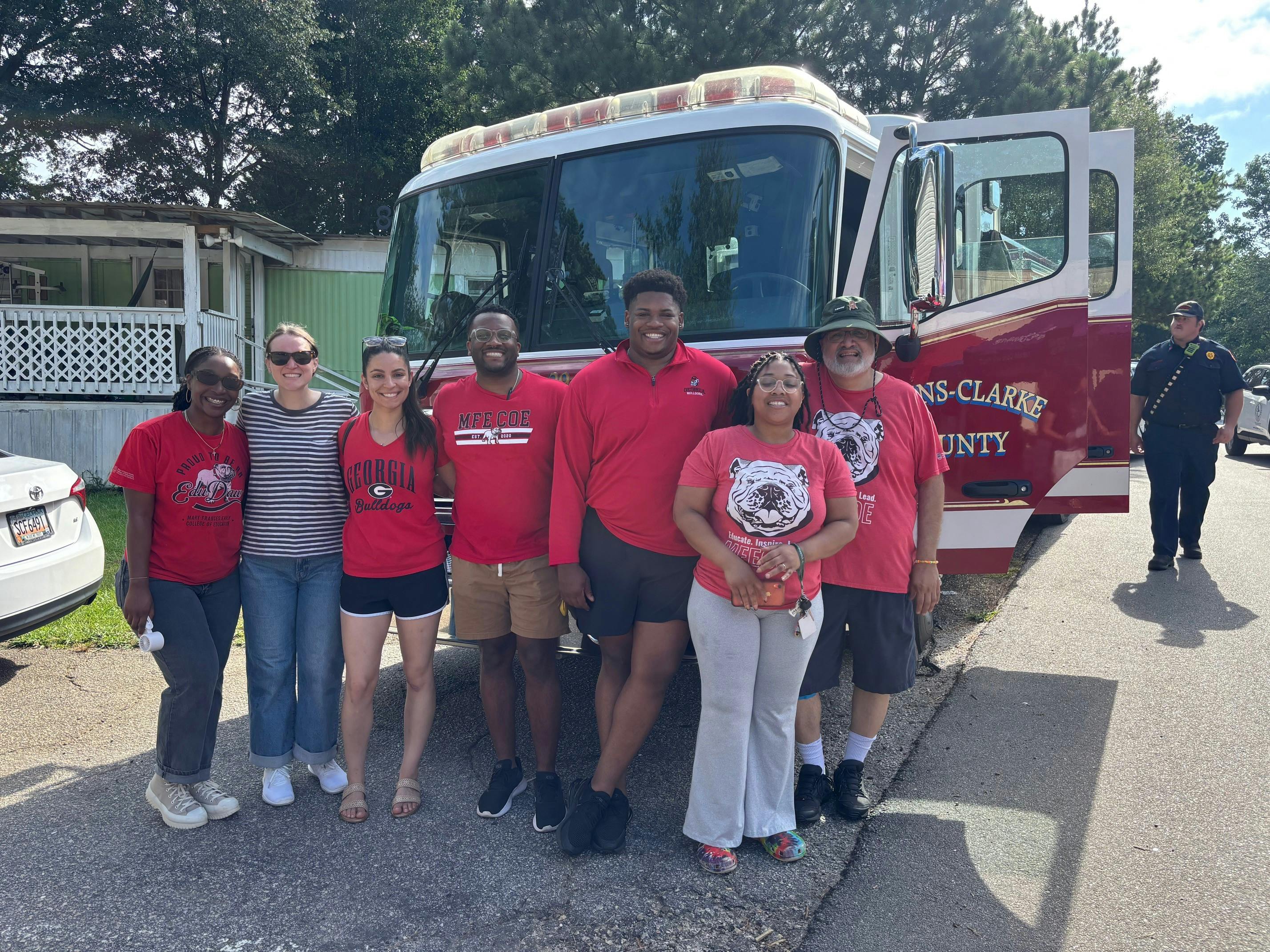 Doctoral students and Dr. Edward Delgado-Romero pose in front of a firetruck at the Pinewoods Library