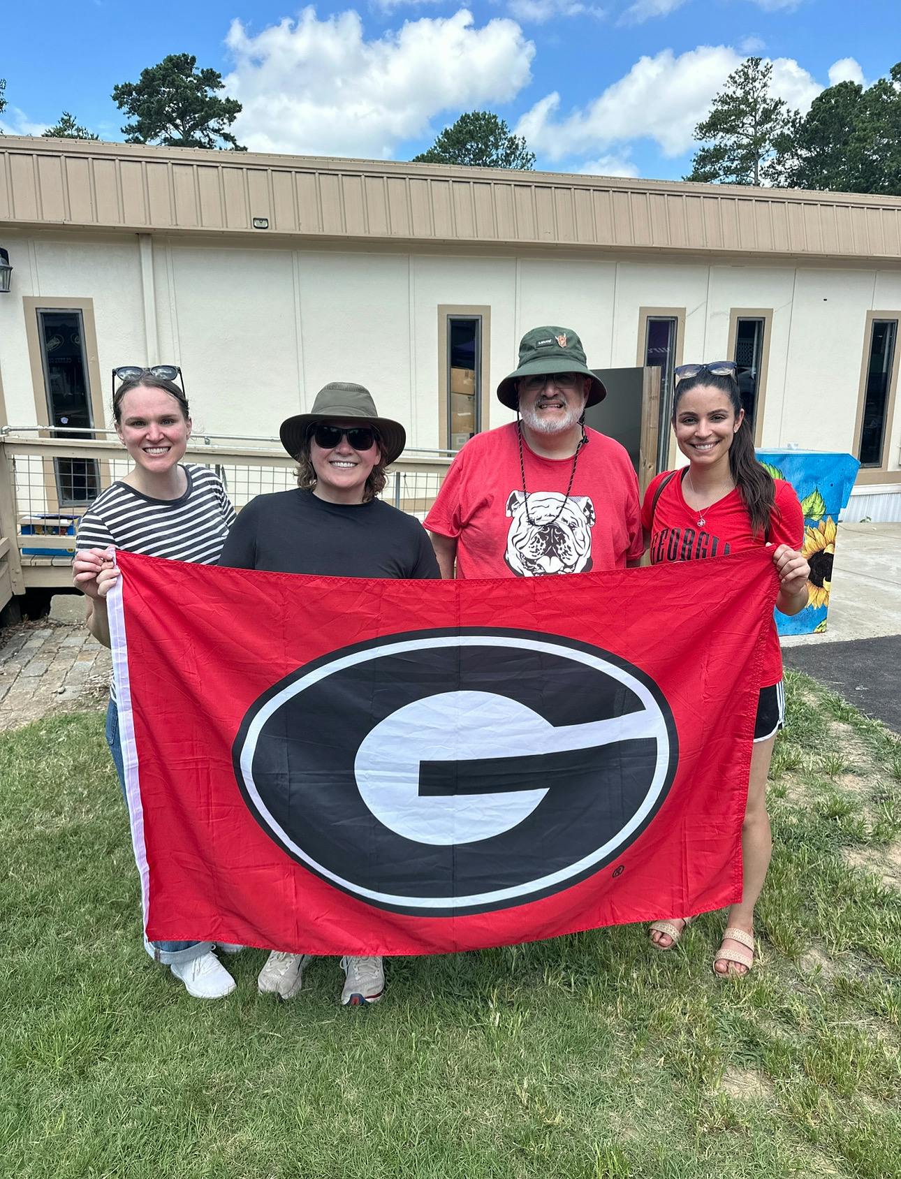Doctoral students and Dr. Edward Delgado-Romero pose holding a UGA flag