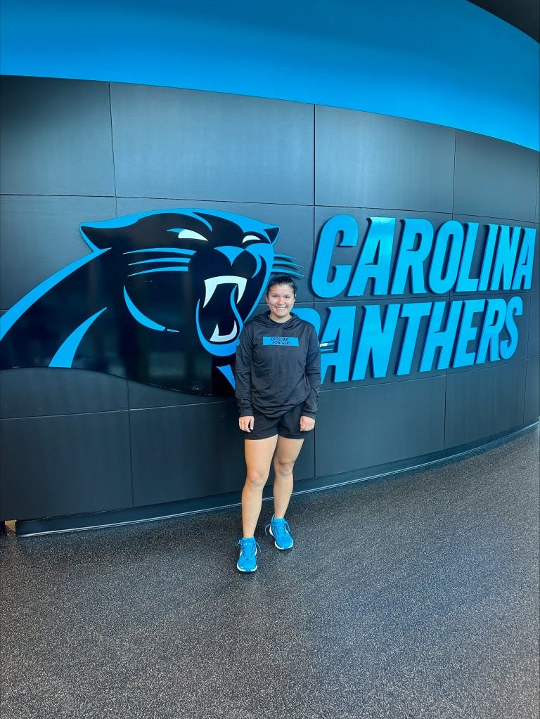 Photo of Qwynn Marquez in front of a Carolina Panthers-themed wall.